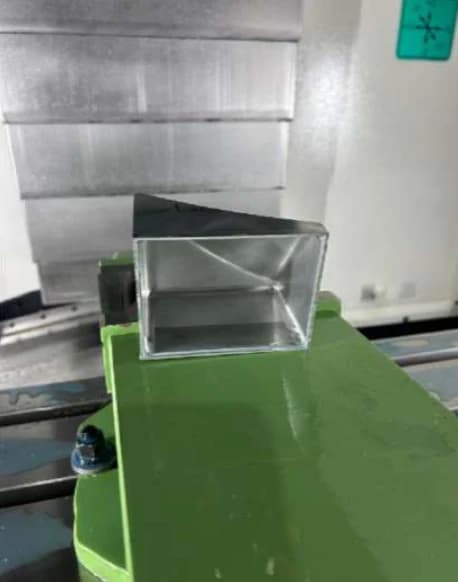Machined metal housing held in a fixture on the shop floor